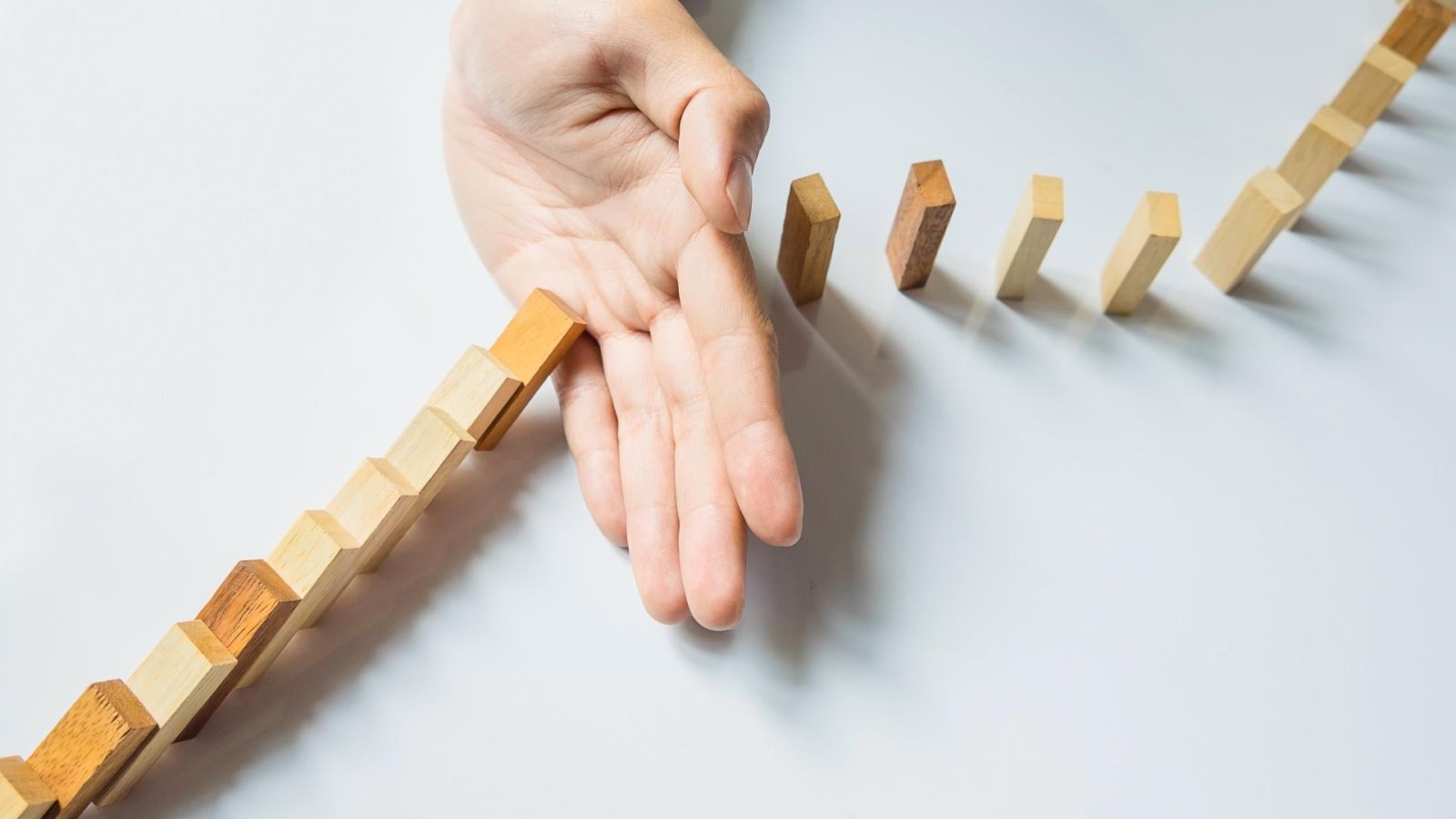 empresario-mano-parada-domino-continua-derribado-o-riesgo-copyspace