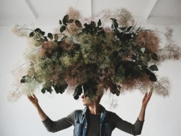 gran-ramo-decorativo-hecho-hojas-verdes-musgo-cuelga-sobre-cabeza-hombre